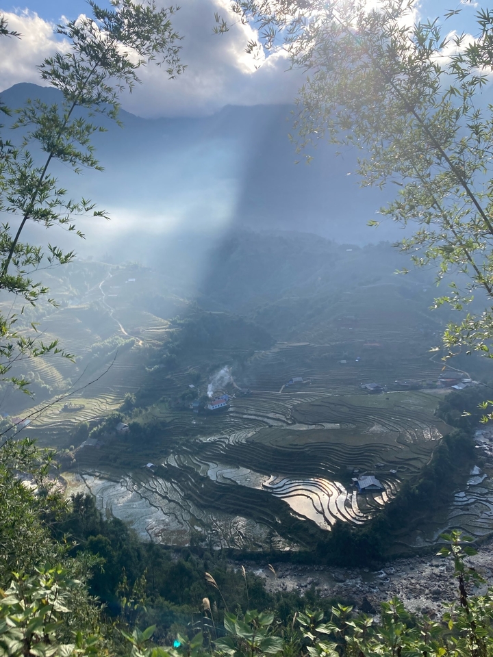 Scenic view of terraced fields with sunlight streaming through clouds.