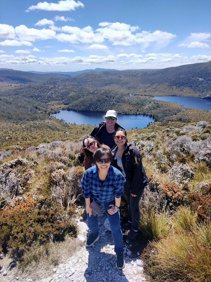 Group of people on a mountain ridge with a lake in the background.