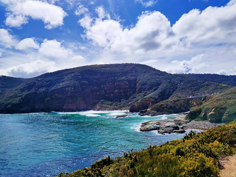 Dramatic coastal view with clear blue water and rugged cliffs.