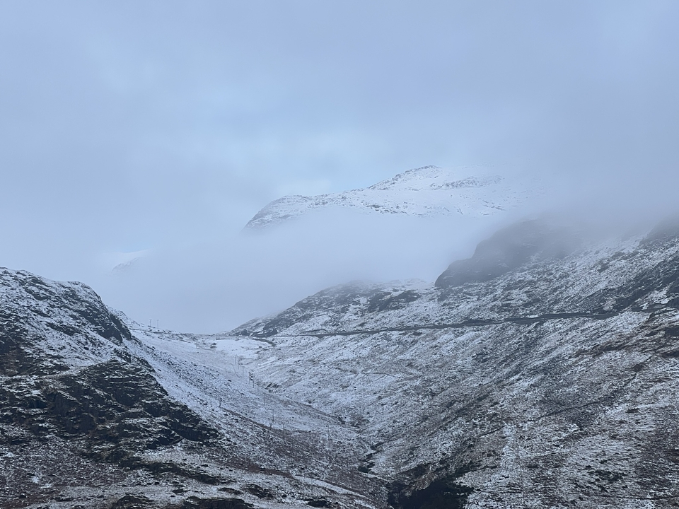 Snow-covered mountains with a road and foggy atmosphere