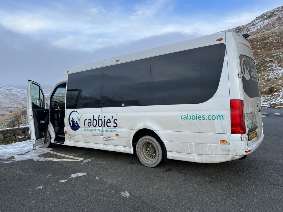 Tour bus parked in a snowy mountainous area.