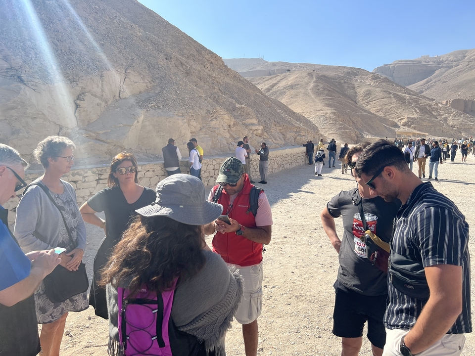 A group of people standing in a desert landscape with mountains in the background.