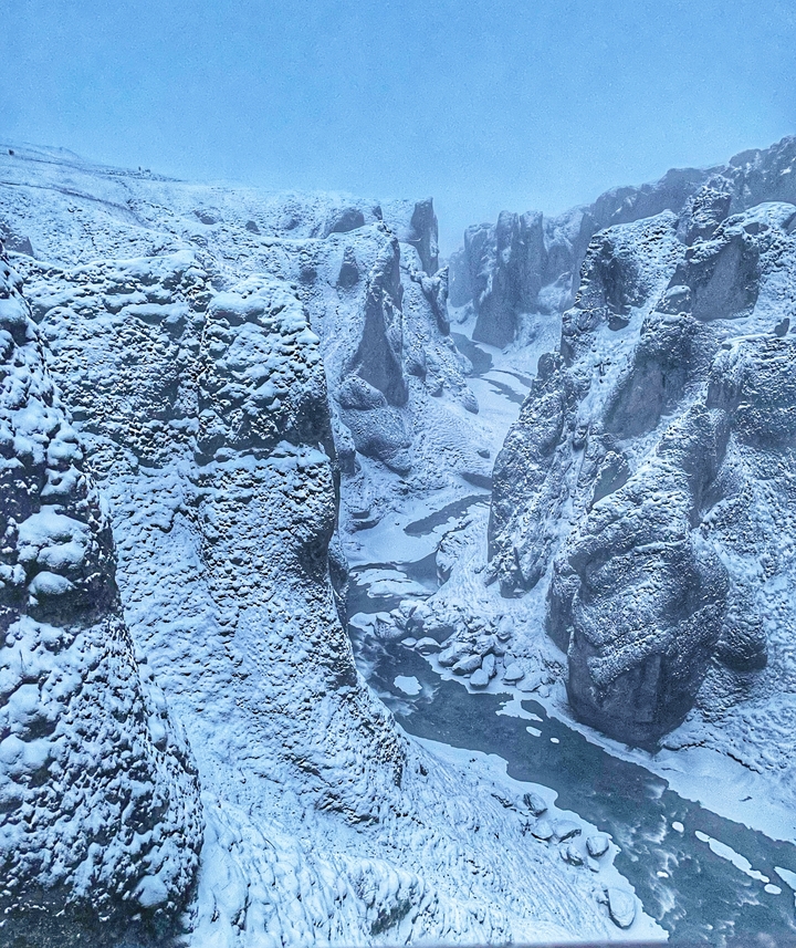 A snowy canyon view with large cliffs.