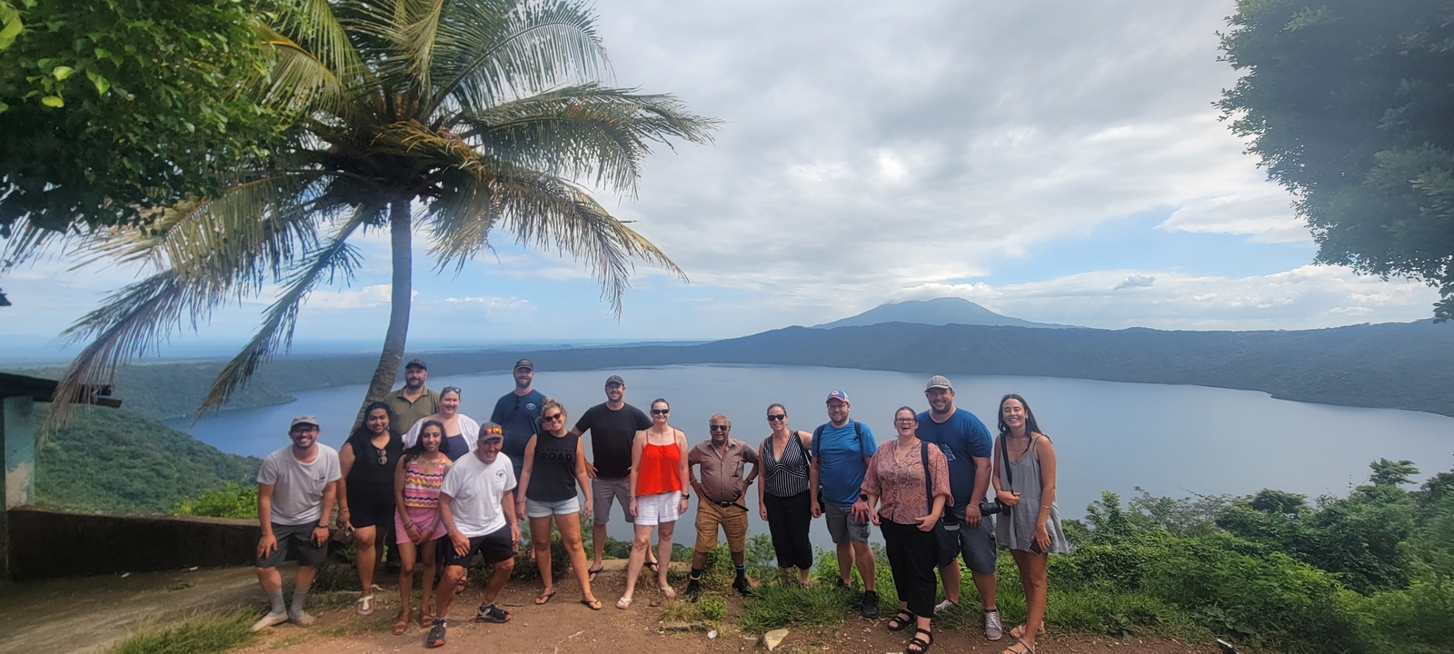Group of people posing in front of a lake with mountainous backdrop.