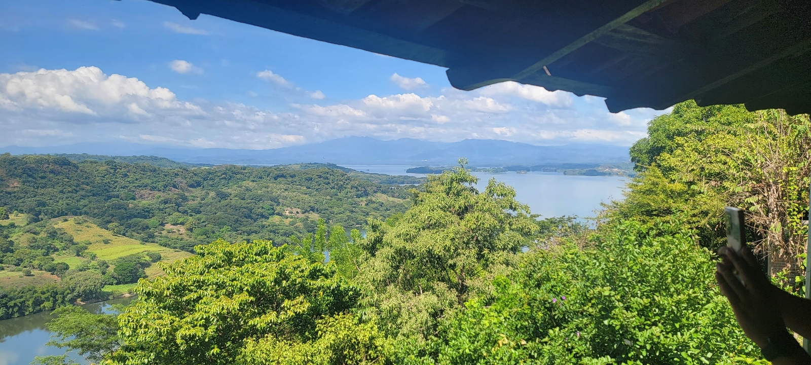 Panoramic view of a landscape with a lake surrounded by greenery.