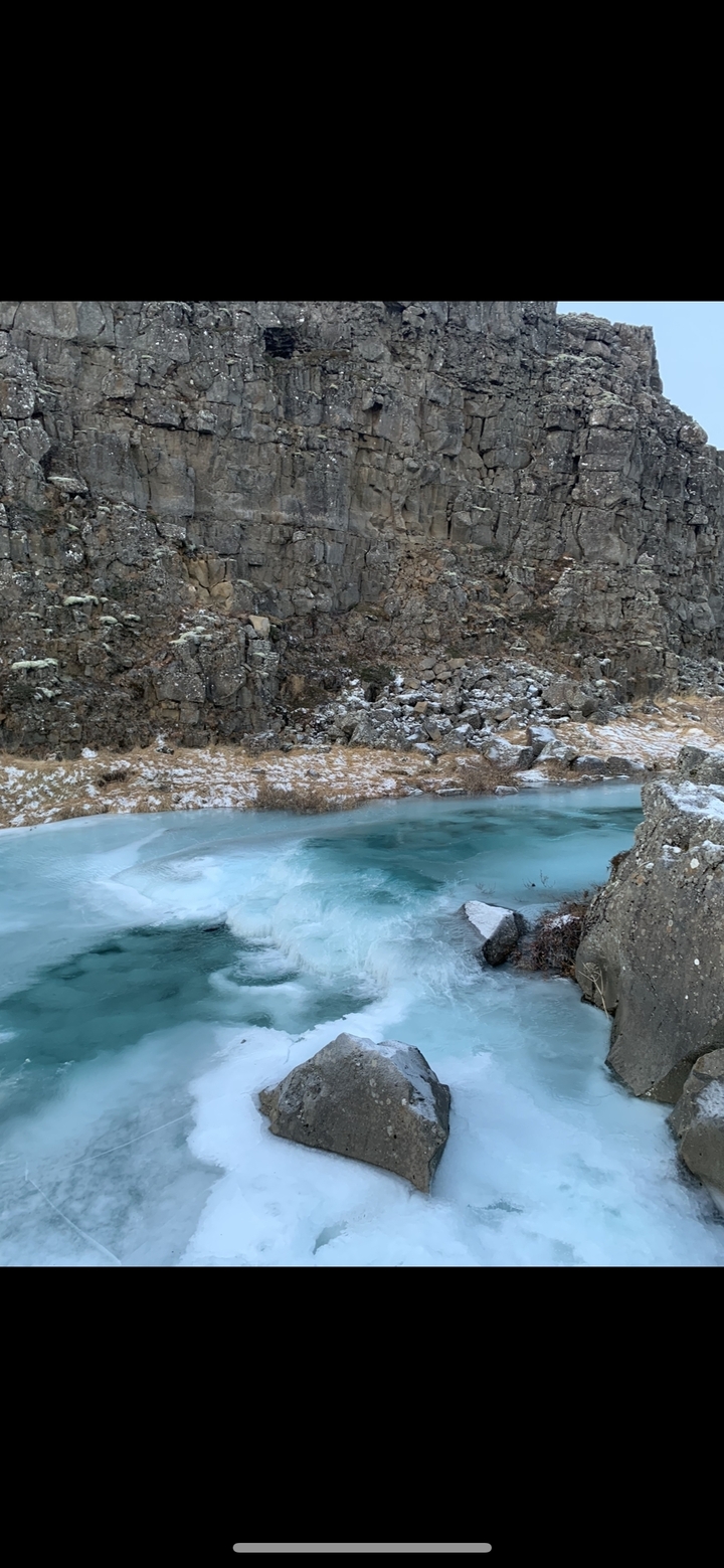 Frozen river flowing through snowy canyon landscape.