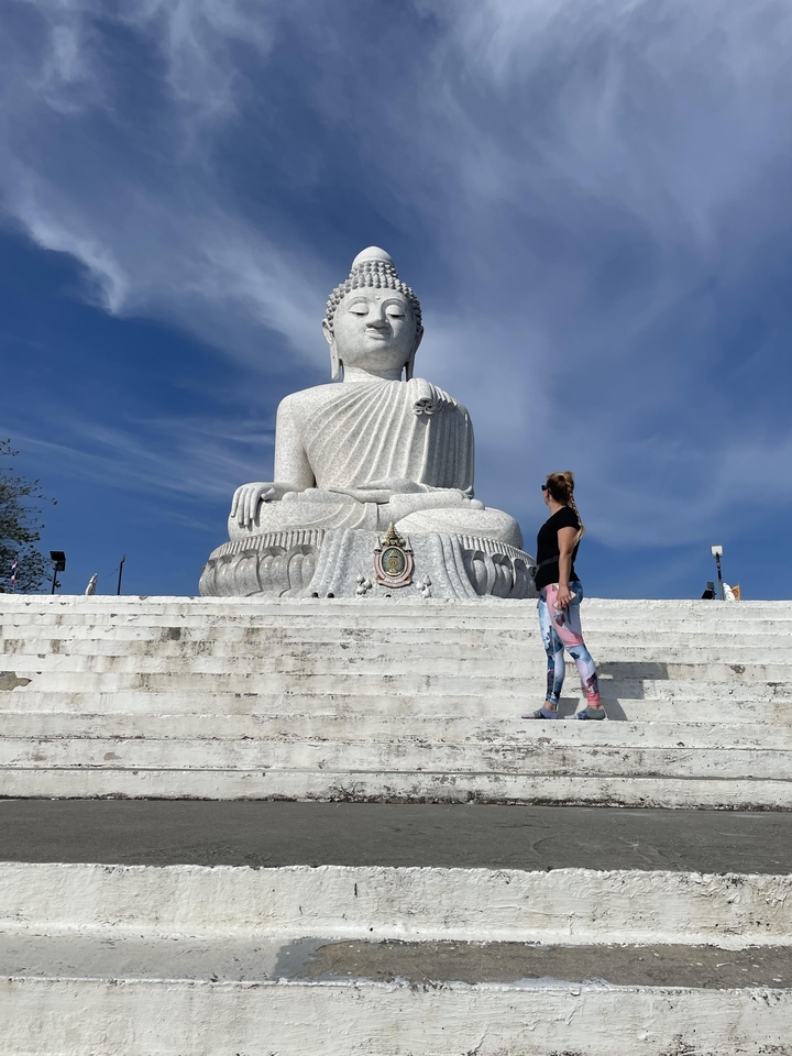 A large white Buddha statue with a person standing in front.