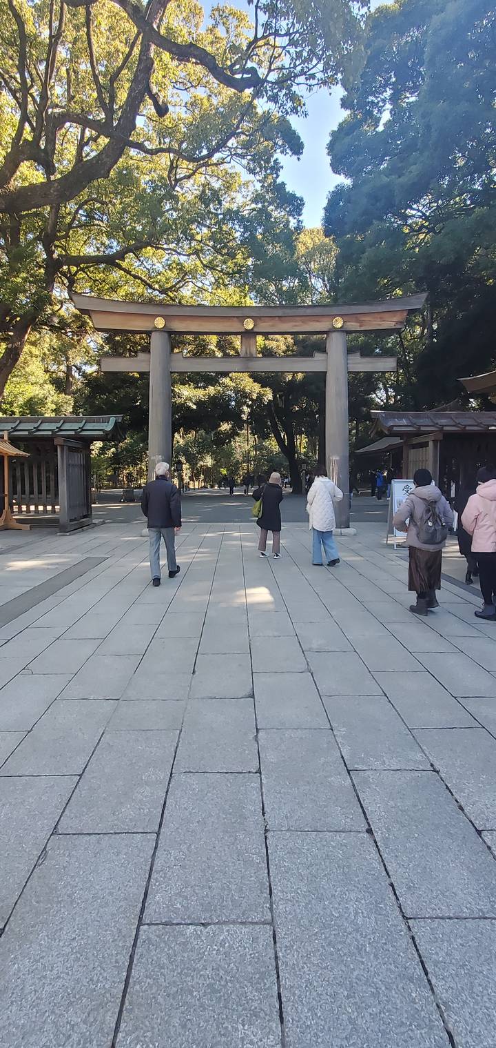 Visitors walking at the entrance of a traditional Japanese shrine.
