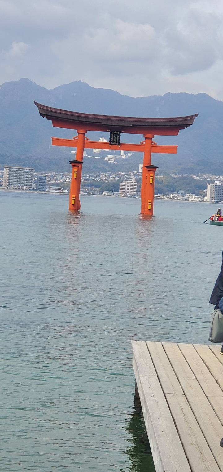 Torii gate at Itsukushima Shrine sitting over water with a mountain backdrop.