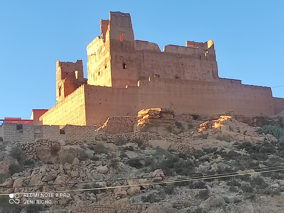 A large historic building on a hill in the desert at sunset.