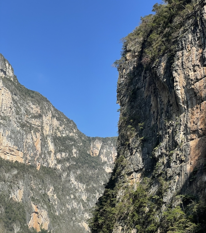 Hautes falaises sous un ciel bleu dégagé, possiblement une vue de canyon.