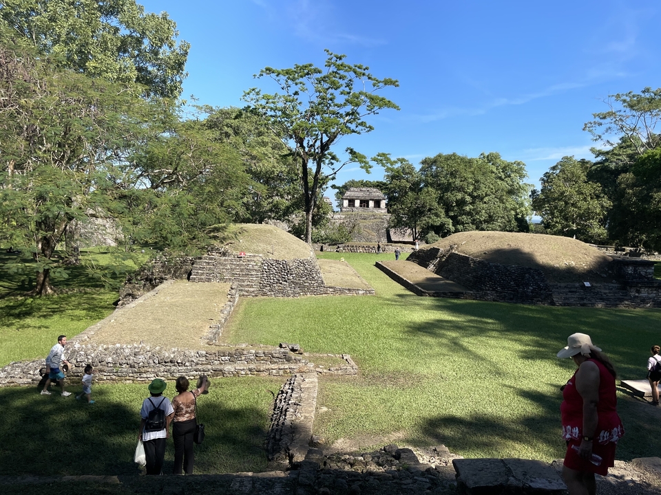 Des gens explorant d'anciennes ruines de pierre et des buttes herbeuses.