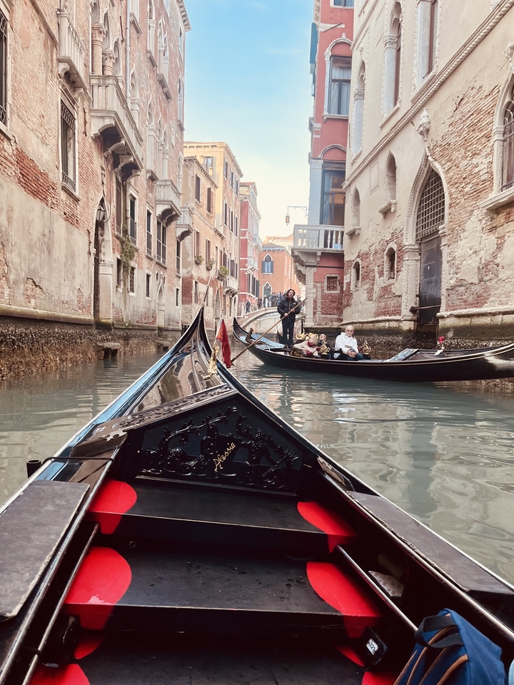 Gondolas on a narrow canal between historic buildings.