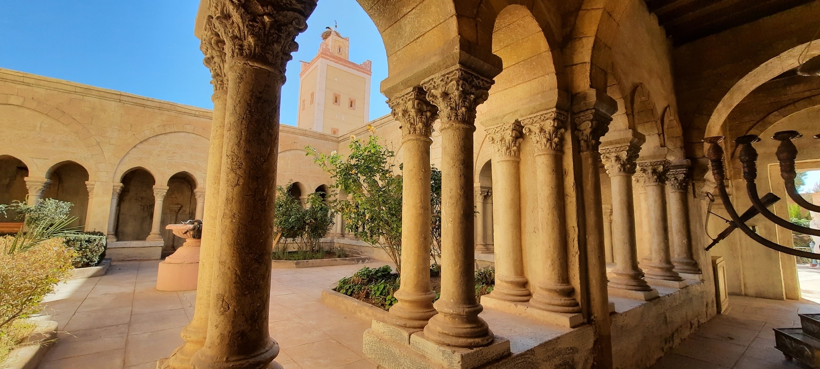 Historical courtyard with stone pillars and a minaret in the background.