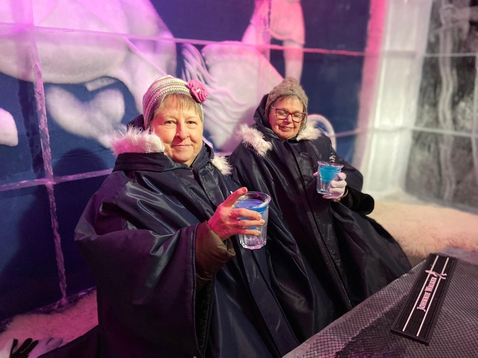 Two people in ice-themed attire holding drinks.