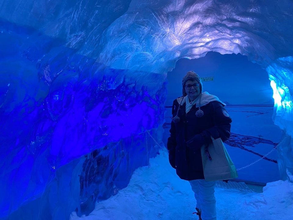 Person inside an ice cave with blue lighting.