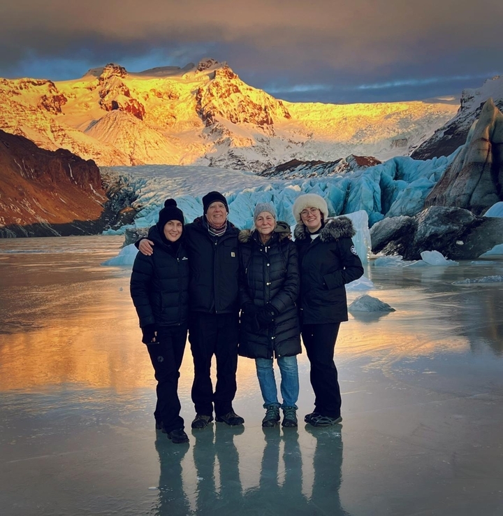Photo de groupe avec des personnes debout sur un sol glacé devant un glacier en arrière-plan.