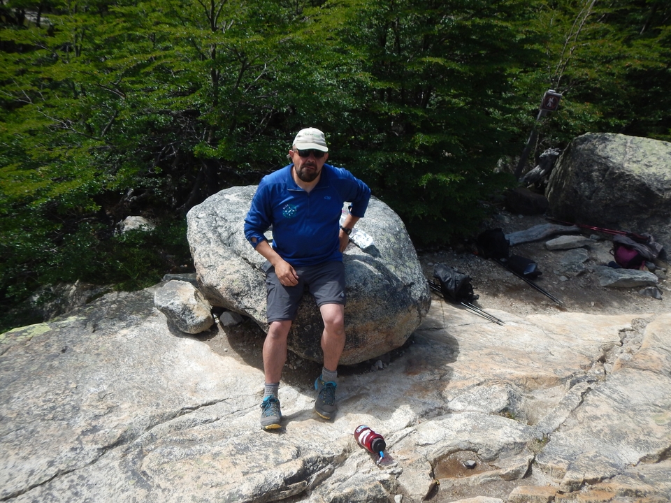 Man sitting on a rock in a natural setting.
