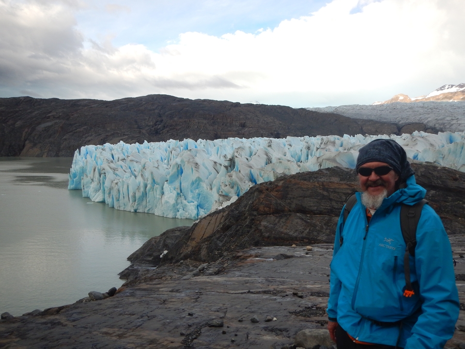 Person in a blue jacket in front of a glacier.
