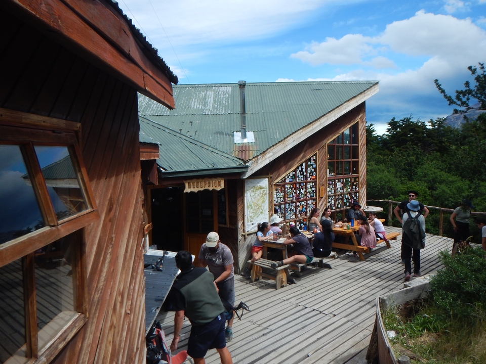 Group of people sitting outside a wooden building in the mountains.