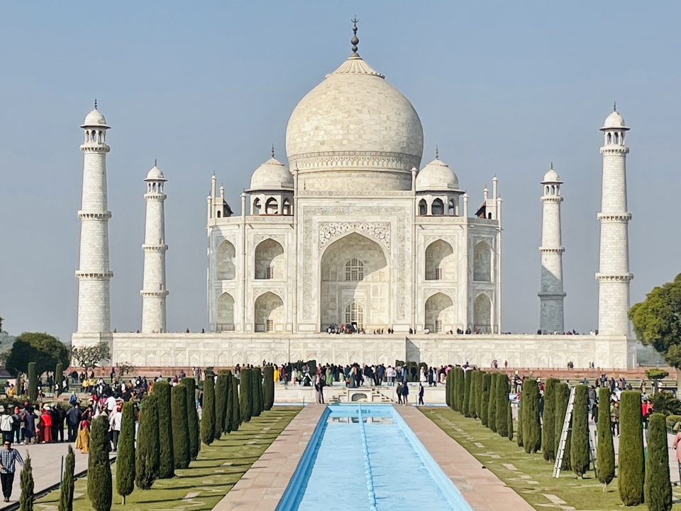 The Taj Mahal with tourists walking in the foreground.
