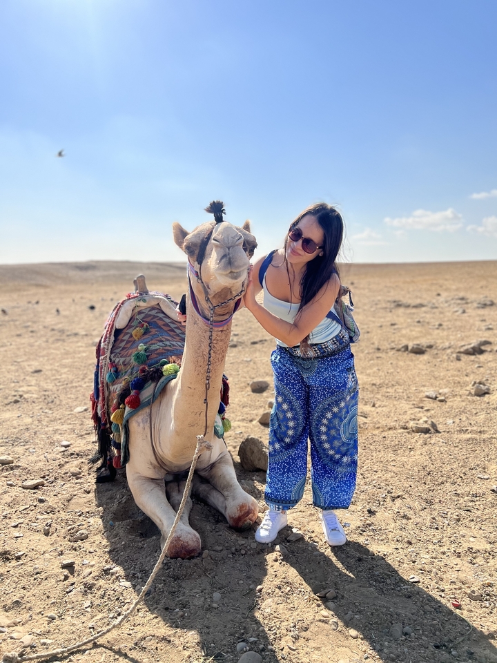 Woman posing with a camel in the desert.