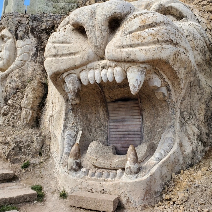 Carved stone face of a lion with mouth open.