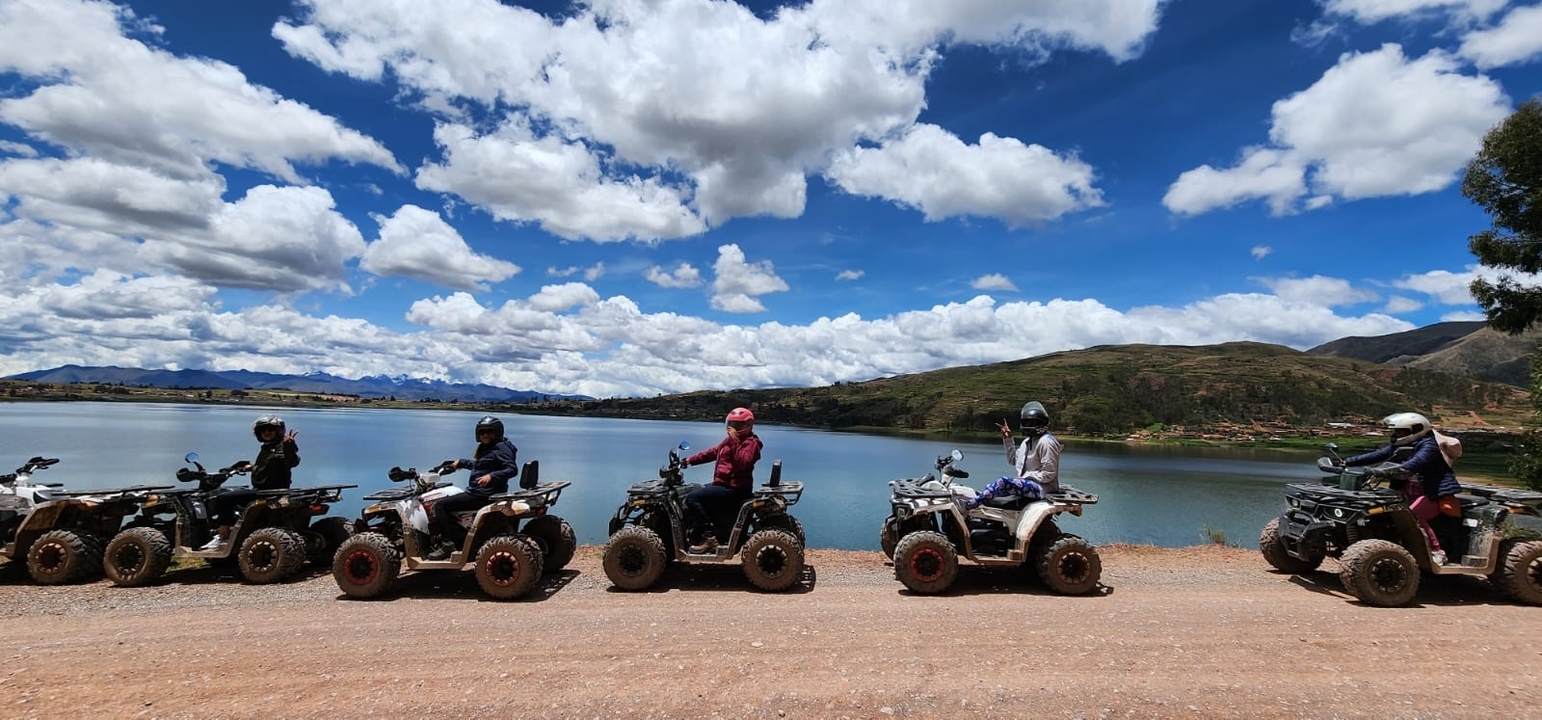 People riding quad bikes alongside a scenic lake.
