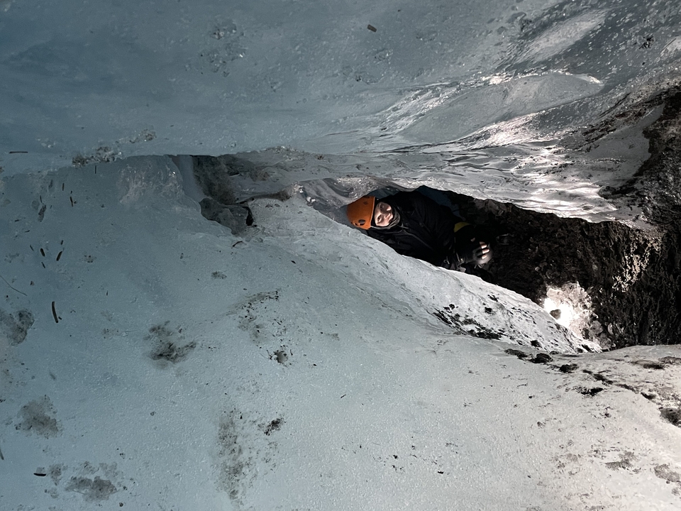 Person exploring an ice cave from inside.
