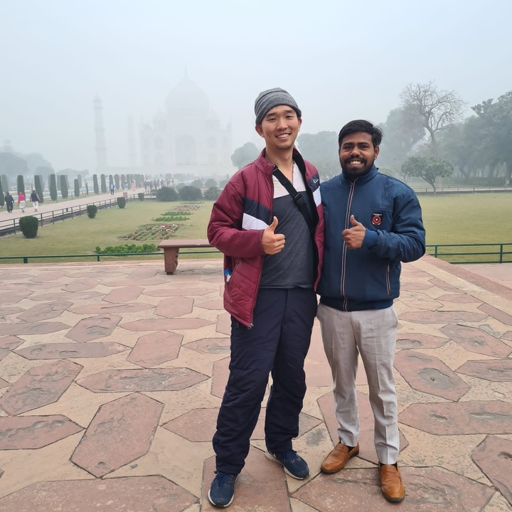 Two people posing on stone pavement in front of Taj Mahal.