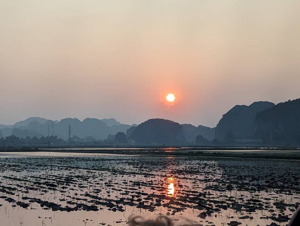 Coucher de soleil sur un paysage serein avec des montagnes et de l'eau.