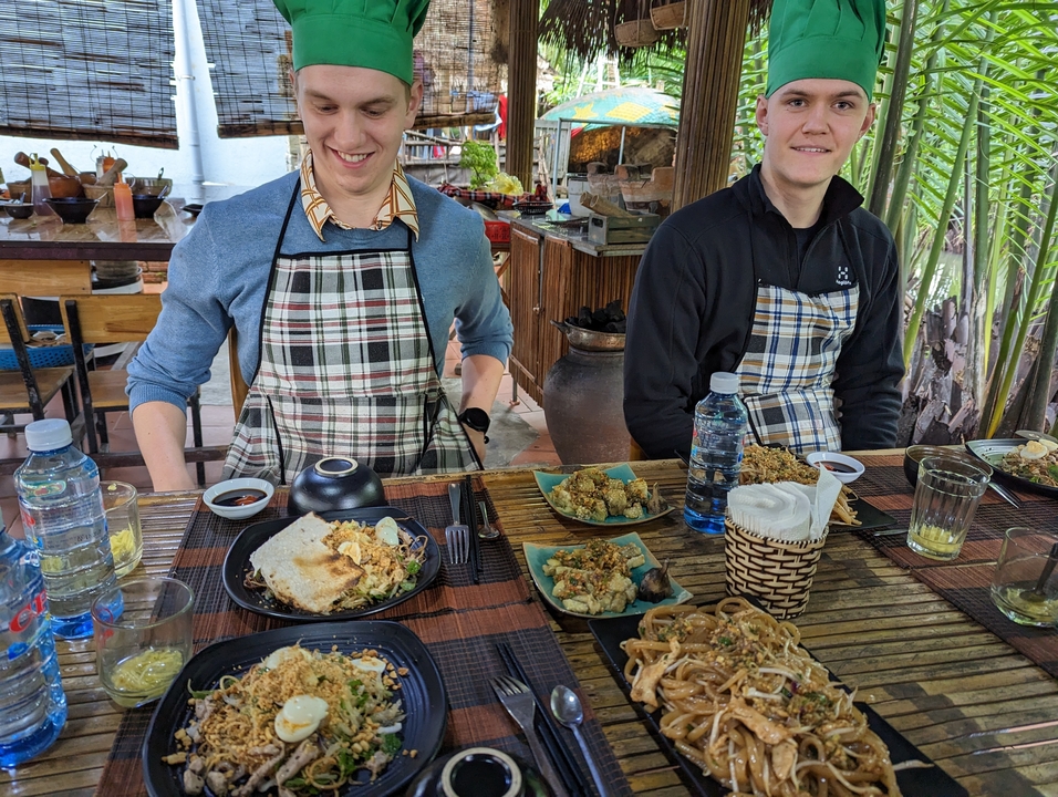 Des personnes savourant un repas à une table rustique avec des plats vietnamiens traditionnels.
