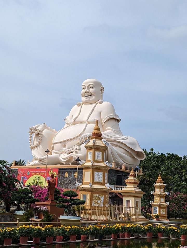 Statue de Bouddha blanc massif contre un ciel bleu.