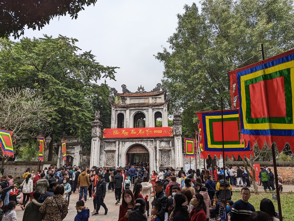 Entrée d'un temple avec des décorations festives et une foule.