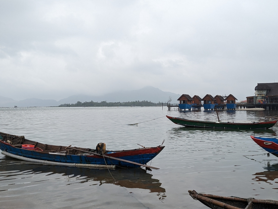 Maisons flottantes et bateaux sur un lac brumeux.