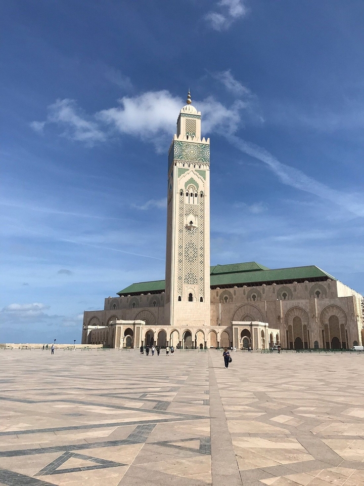 Een grote moskee met een hoge minaret onder een heldere hemel.