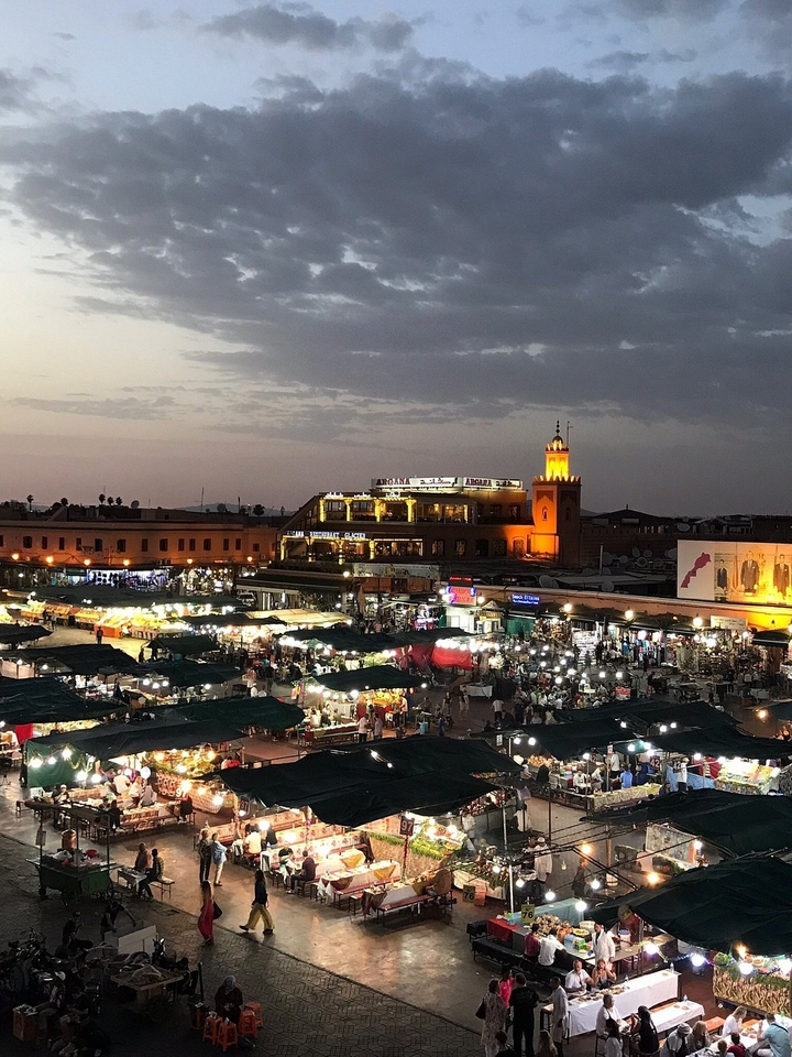 Nachtaanzicht van een drukke markt met verlicht gebouw en toren.