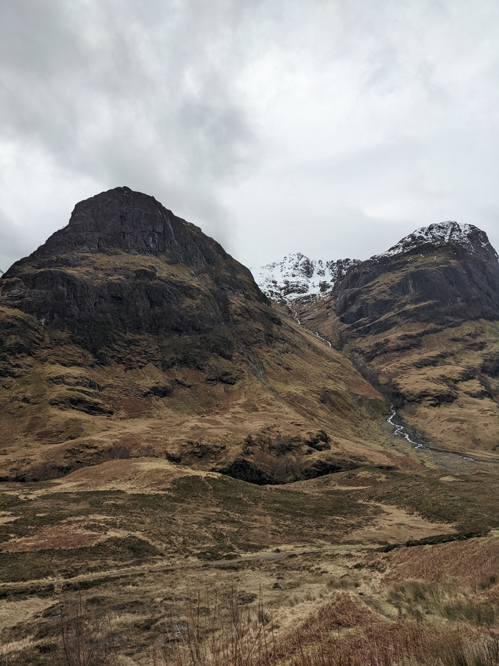 Dramatic landscape of mountains with a snowy peak.