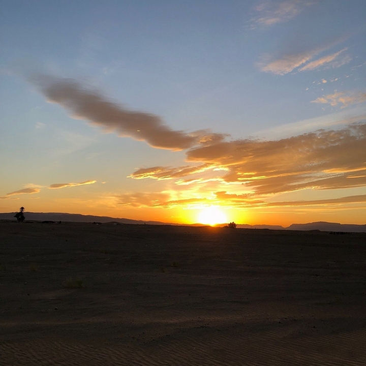 Zonsondergang over een woestijn met dramatische lucht.