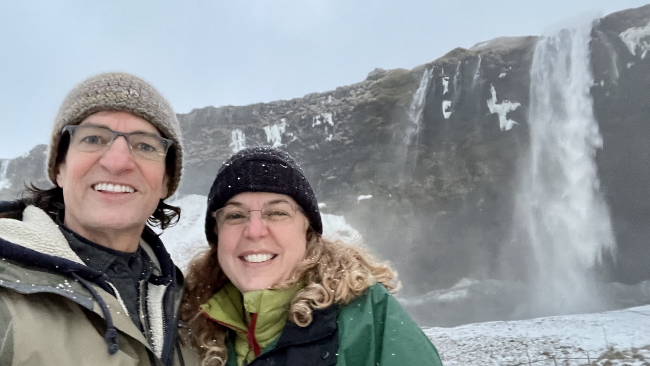 Couple taking a selfie in front of a waterfall during winter.