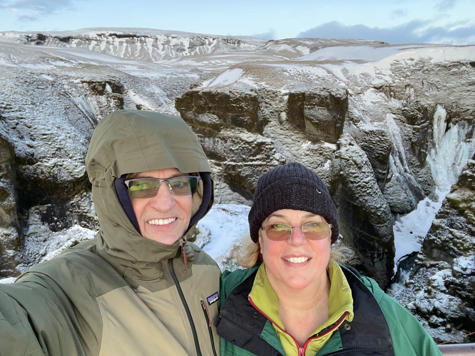 Couple taking a selfie with a snowy canyon in the background.
