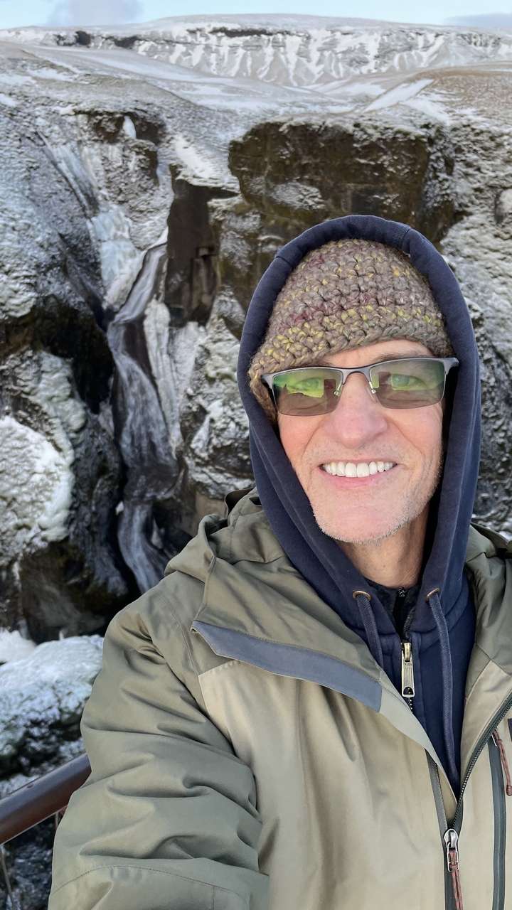 Selfie of a person with rocky terrain in the background.