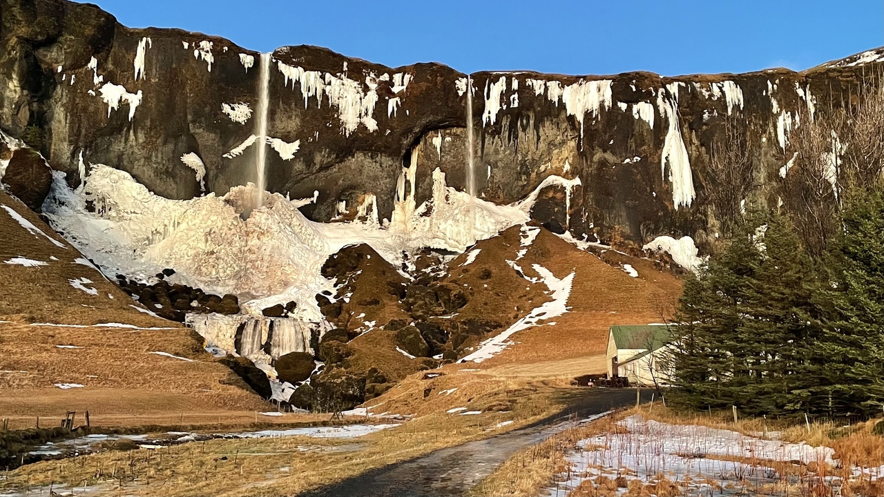 Scenic landscape with frozen waterfalls cascading down cliffs.