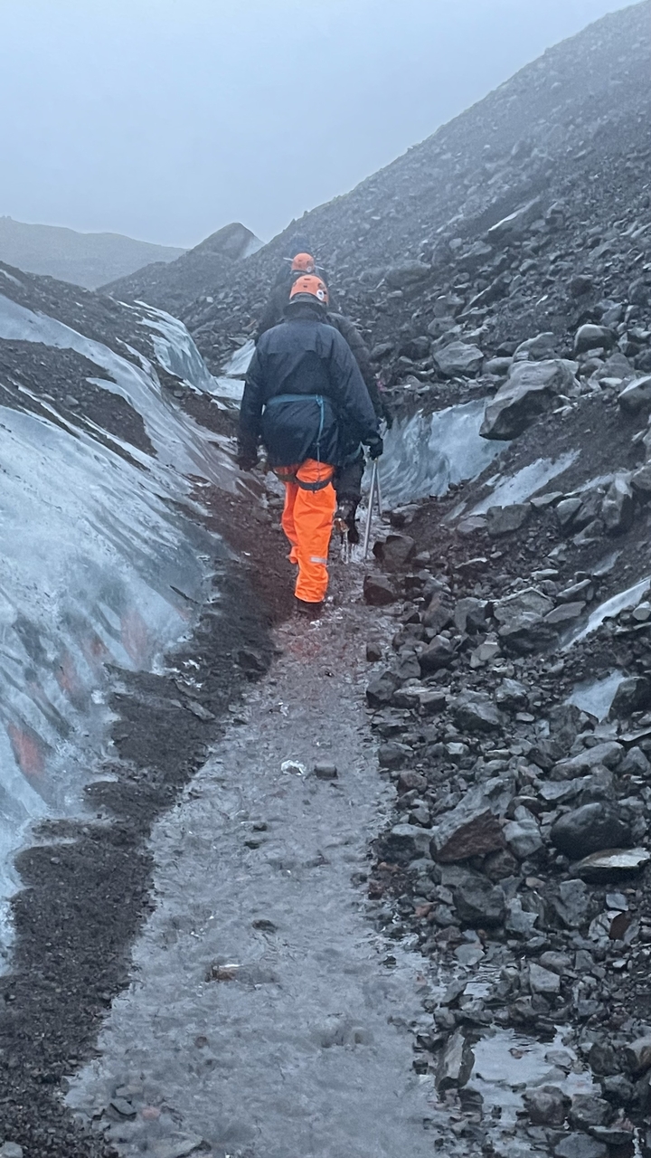 Person walking on a glacier with hiking equipment.