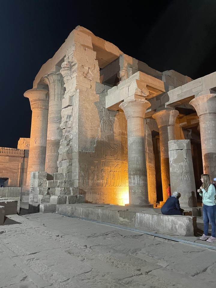 Ancient Egyptian temple with illuminated hieroglyphics at night.