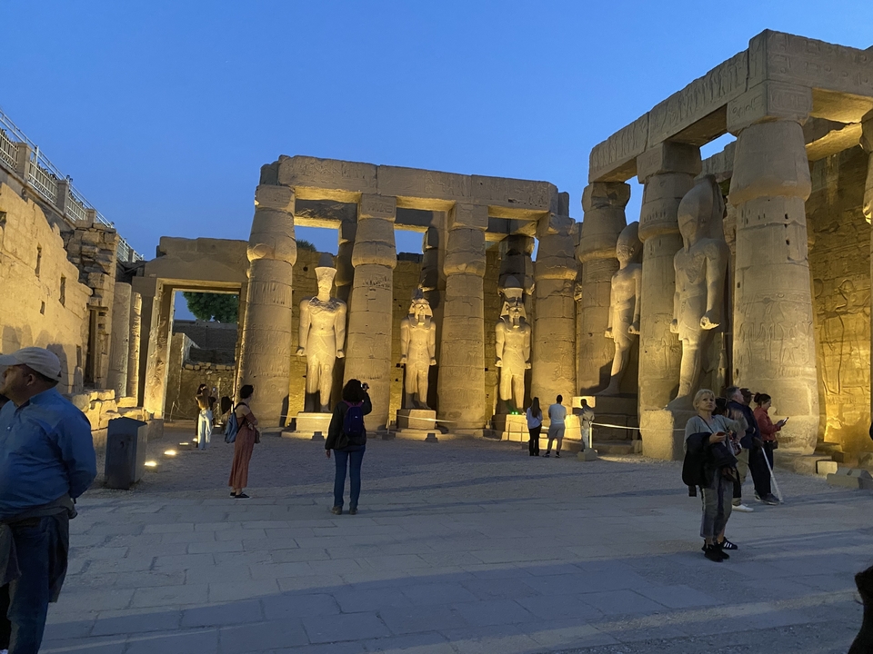 Illuminated ancient columns with carved statues at night.