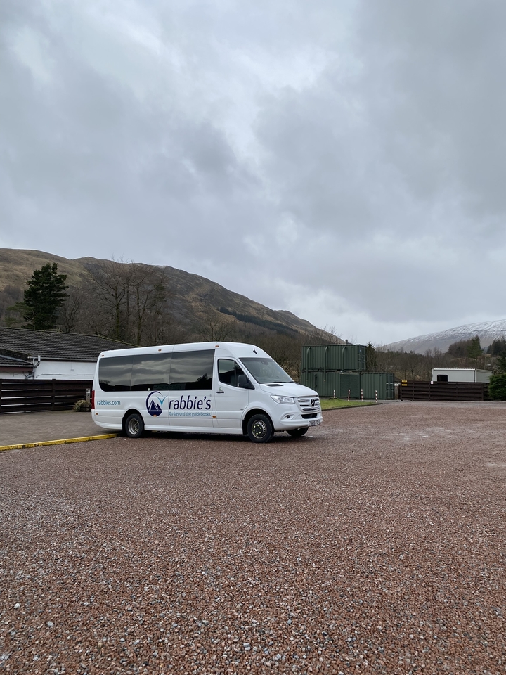 Autocar de tourisme garé dans une région montagneuse par temps nuageux.