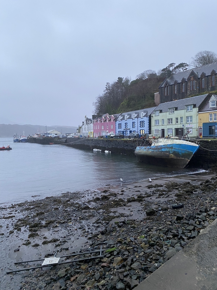 Village côtier coloré avec des bateaux et un ciel nuageux.