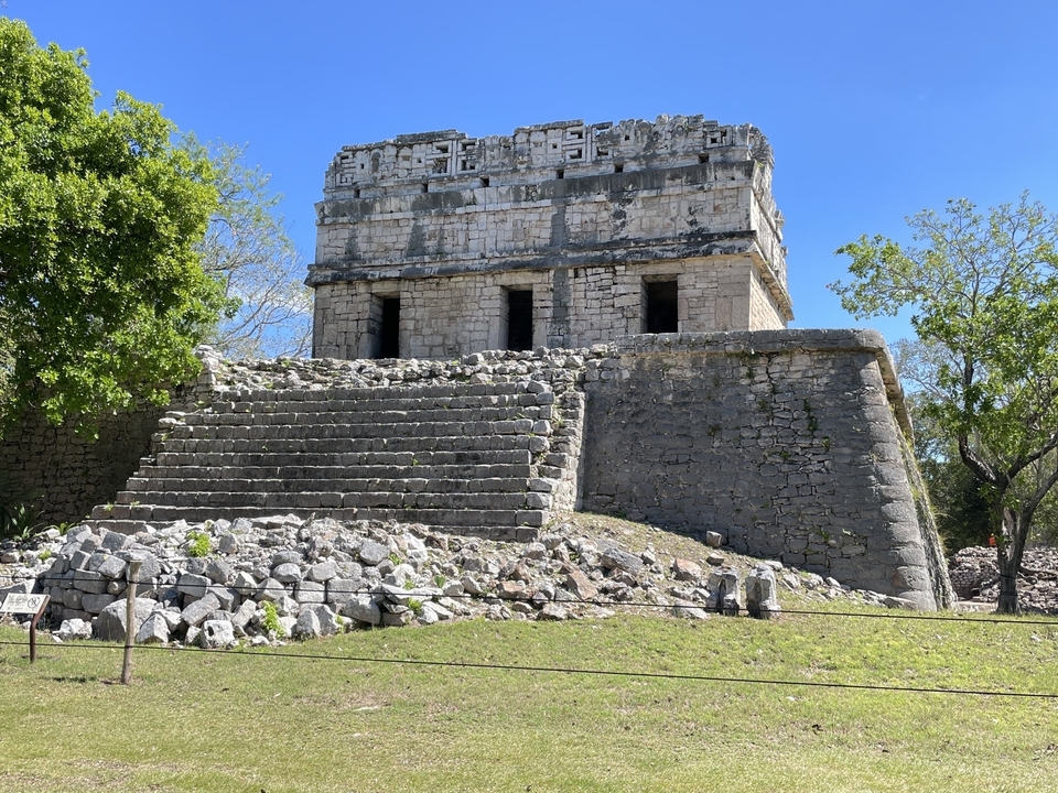 Small Mayan temple ruins surrounded by greenery.