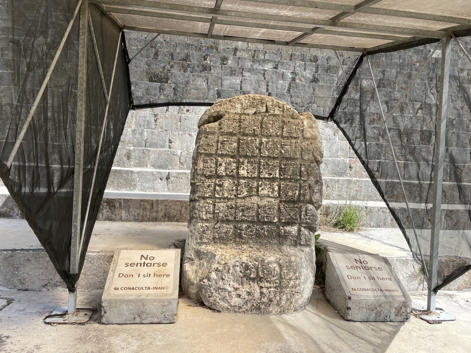 Stone stela with inscriptions at an archaeological site.